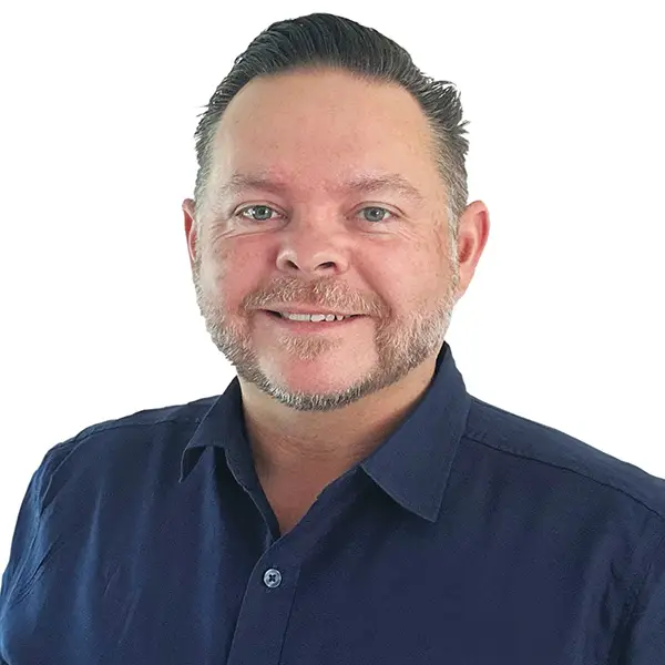 Professional portrait of Scott McCartney, smiling, wearing a navy collared shirt, against a white background.