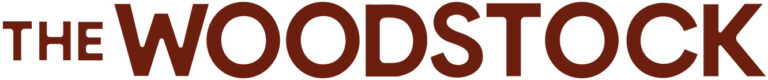 The Woodstock logo featuring the words "THE WOODSTOCK" in bold uppercase sans-serif lettering in deep dark red, with "THE" in a smaller weight and "WOODSTOCK" in a larger, heavier weight, on a white background.