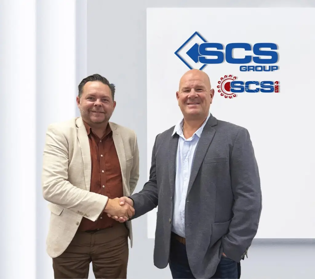 SCS Group Co-Founders Scott McCartney and Nicholas Pastras shaking hands in front of a display board featuring the SCS Group and SCS Indigenous logos.